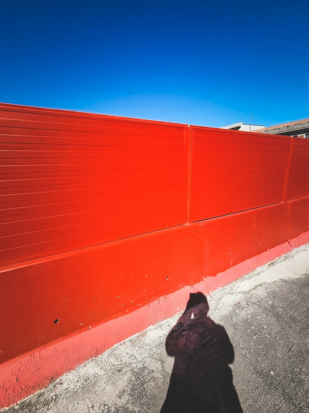 a shadow of a person standing next to a red wall