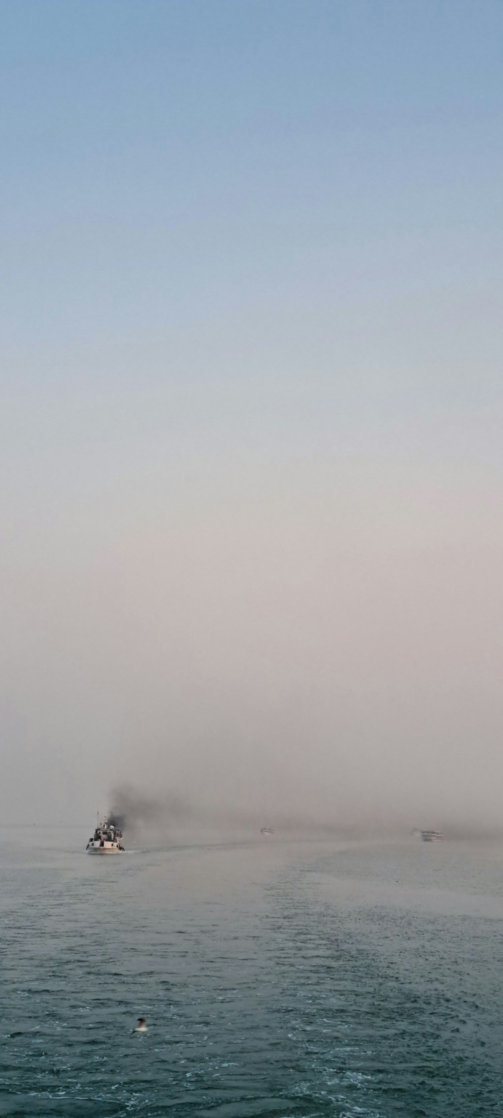 a boat in the middle of the ocean on a foggy day