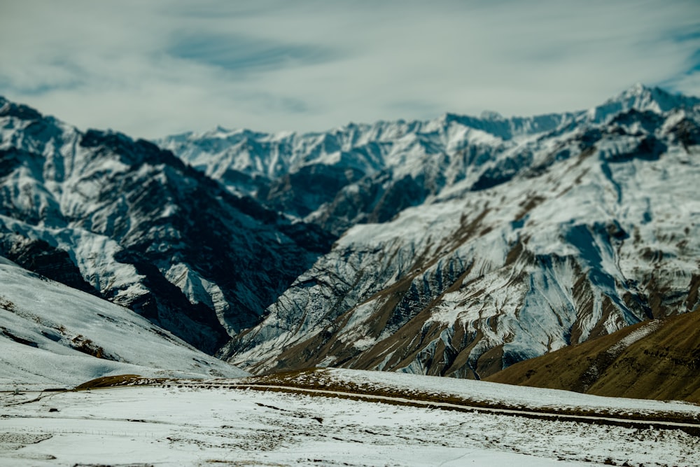 a snow covered mountain range with a train on the tracks