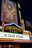 A brightly lit marquee sign with intricate neon lights featuring the Warner Bros logo. The sign advertises 'The Starlight Restaurant' and has art deco style decorations and vibrant colors.