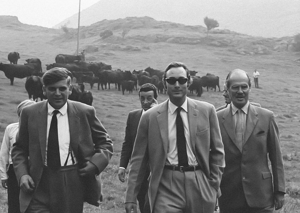 a group of men walking down a grass covered field