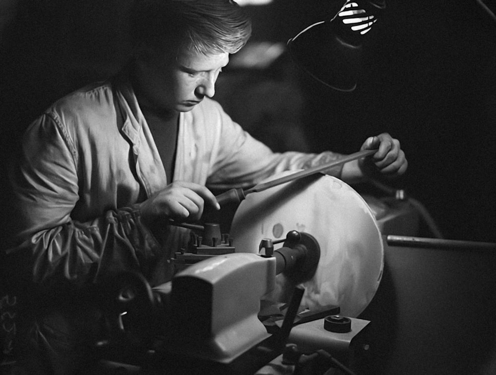 a black and white photo of a man working on a machine