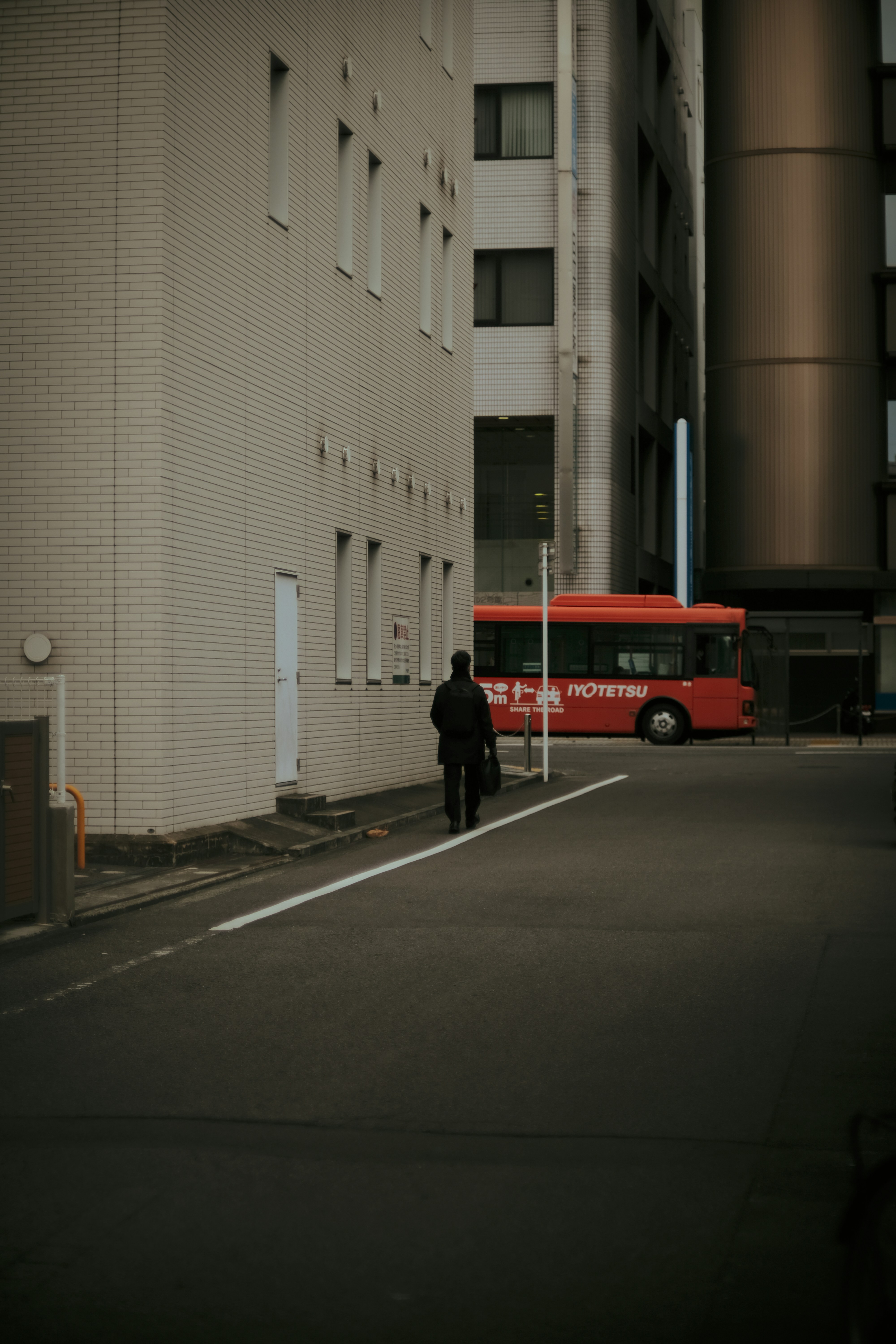 a red bus driving down a street next to tall buildings
