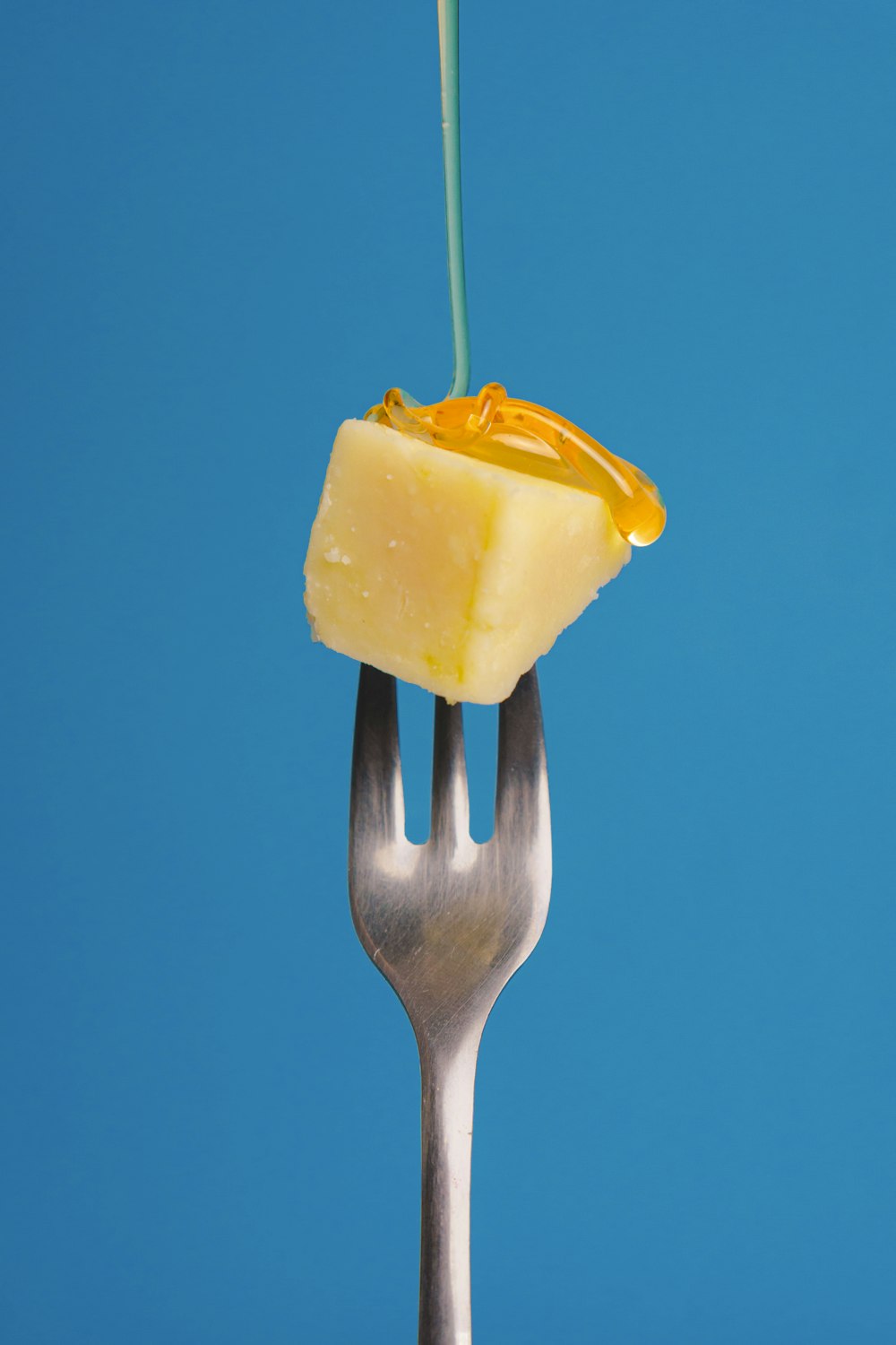 a fork with a piece of cheese on top of it
