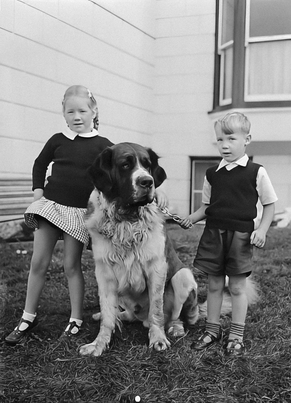 a black and white photo of two children and a dog