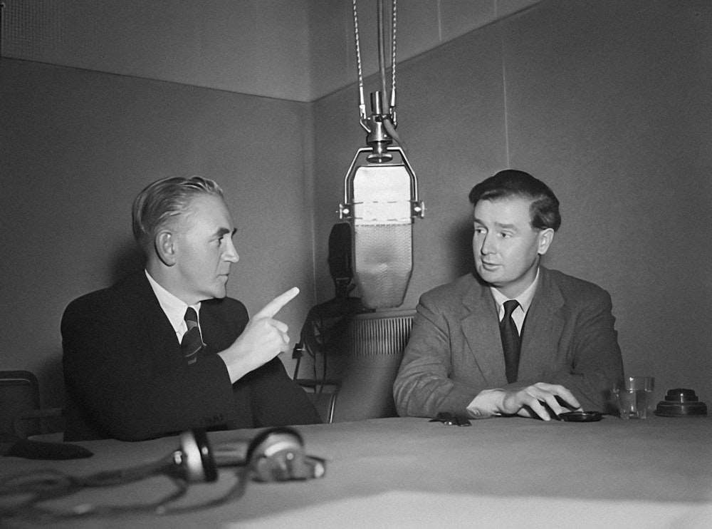 two men sitting at a table talking to each other