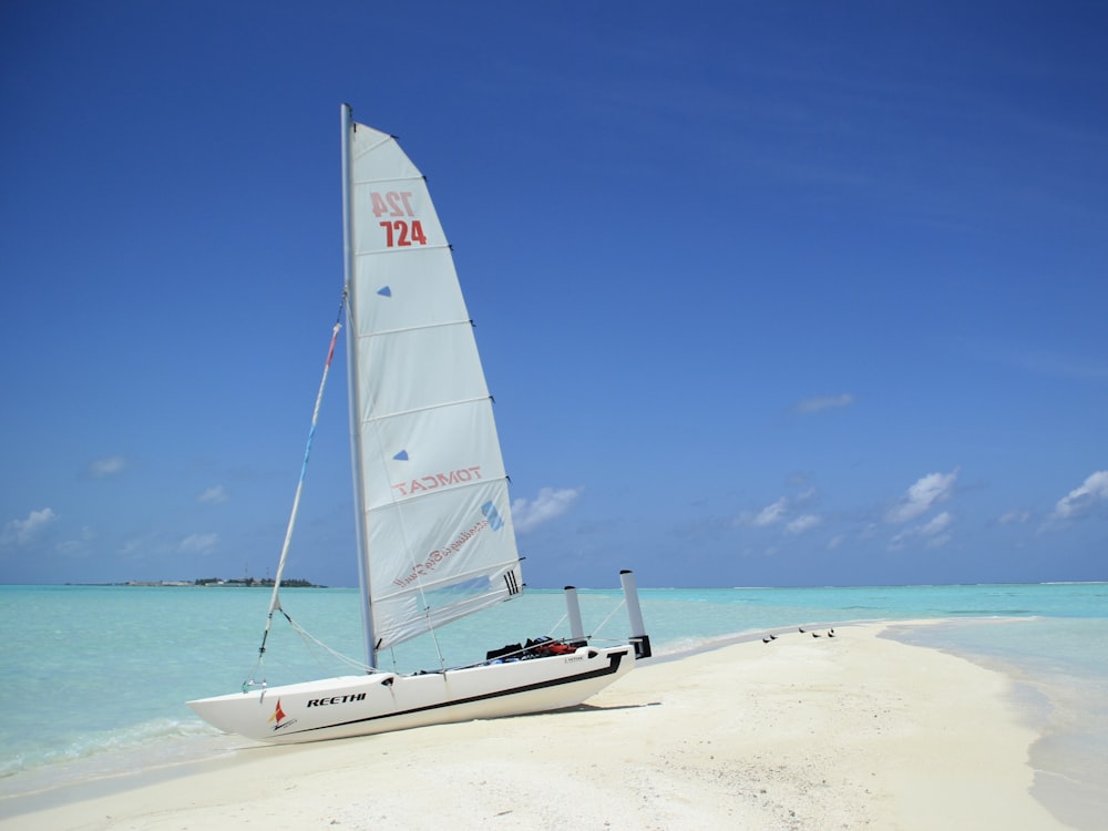 a sailboat on a beach with clear blue water