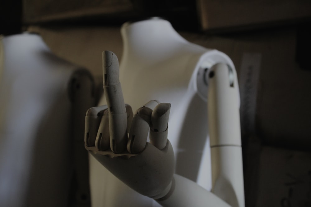 a white mannequin holding up a peace sign