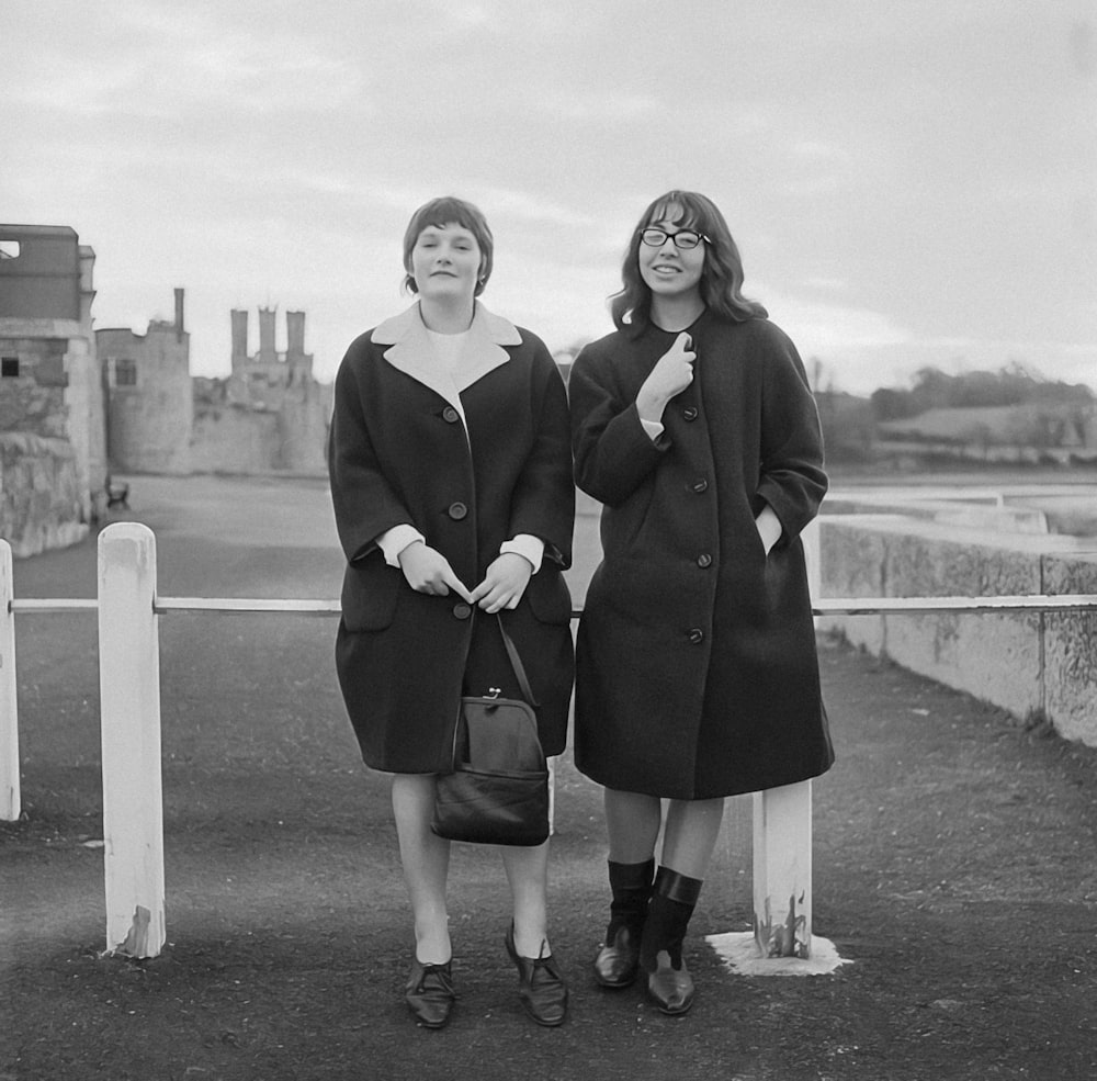 two women standing next to each other in front of a castle