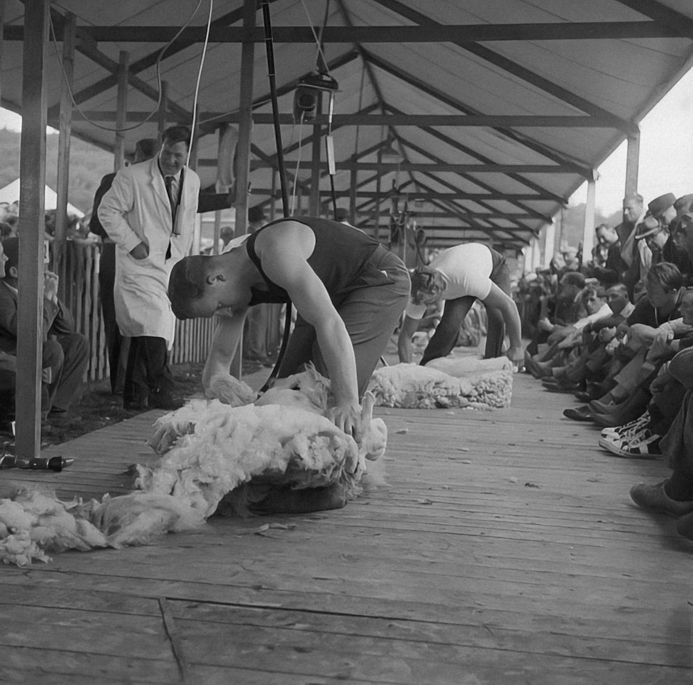 a group of people standing around a pile of wool