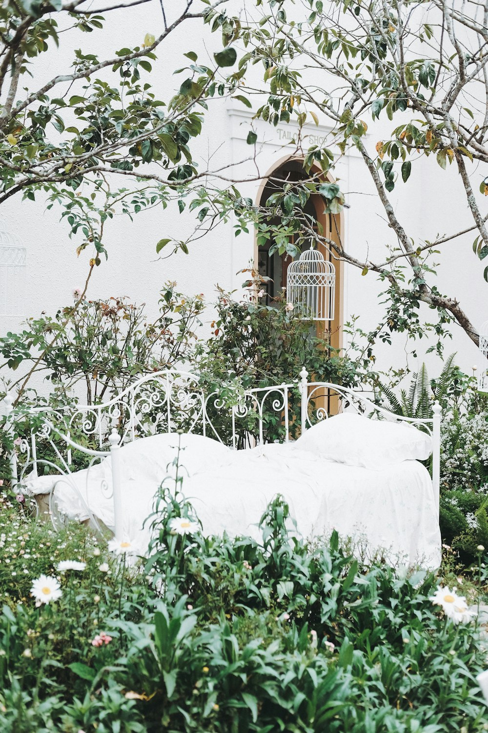 a white bed sitting in the middle of a lush green field