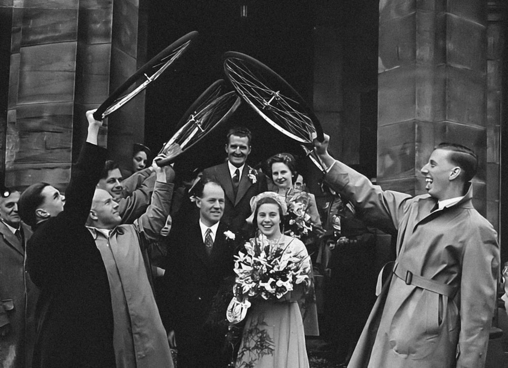 a black and white photo of a bride and groom holding up their tennis rackets