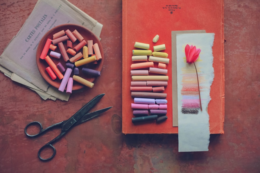 a bunch of crayons sitting on top of a table next to a book