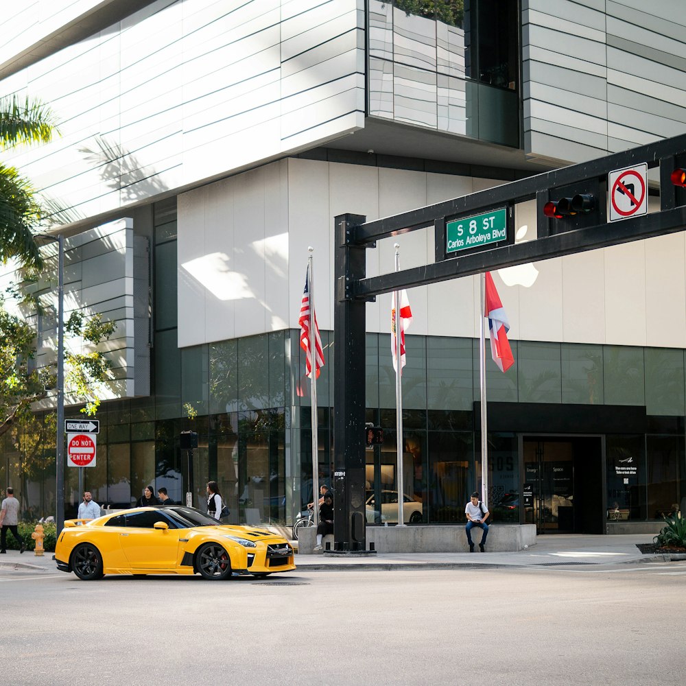 a yellow sports car parked in front of a building