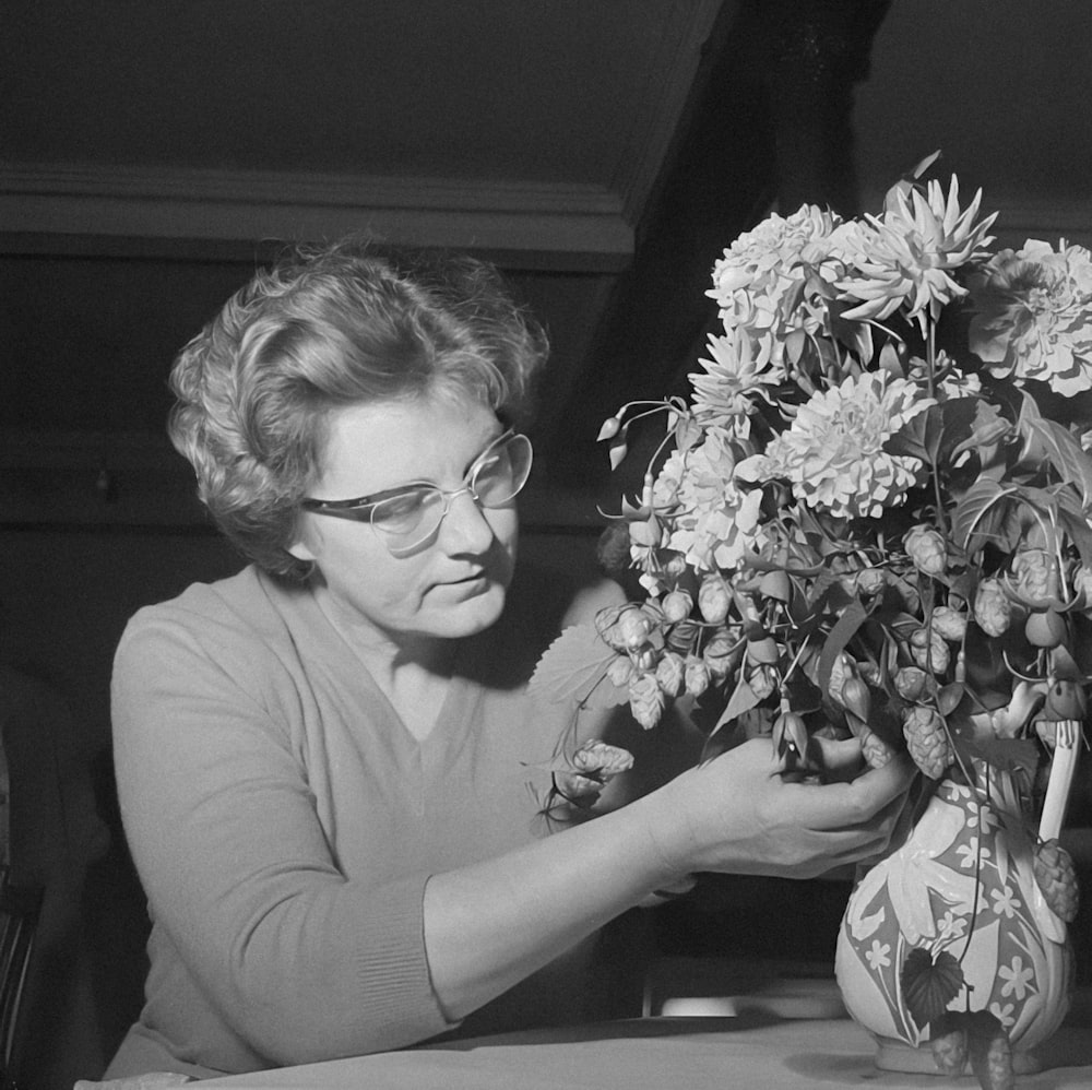 a black and white photo of a woman arranging flowers