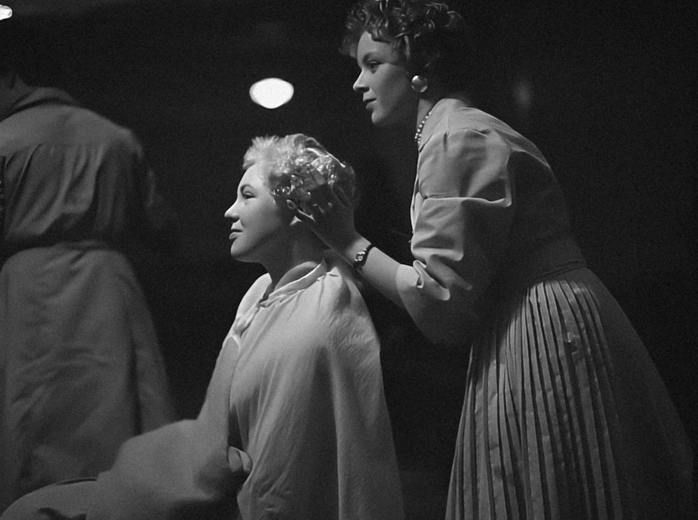 a black and white photo of a woman getting her hair done