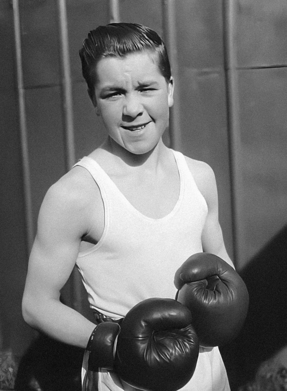 a black and white photo of a boy with boxing gloves