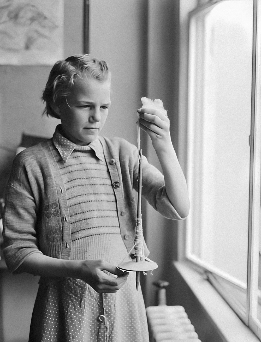 a young girl is holding an umbrella by a window