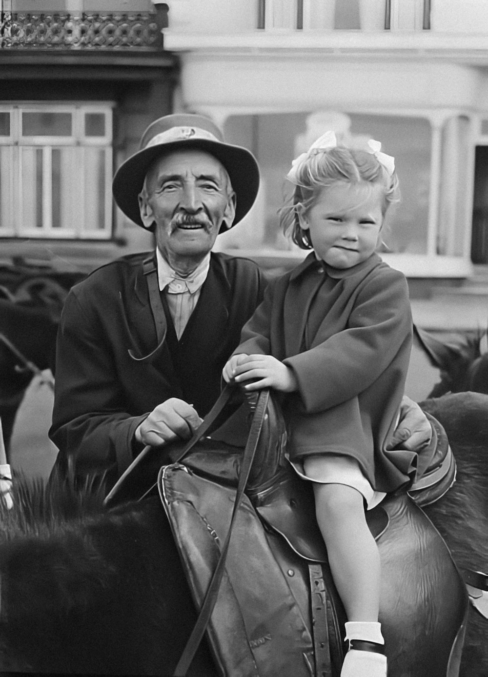 a black and white photo of a man and a child on a horse