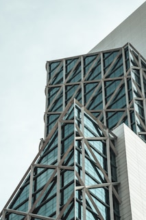 A modern architectural structure with intersecting steel beams and large glass windows. The design features triangular and rectangular elements, giving the building a geometric appearance.
