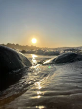 Close-up of gentle waves lapping against smooth stones, bathed in warm evening light.