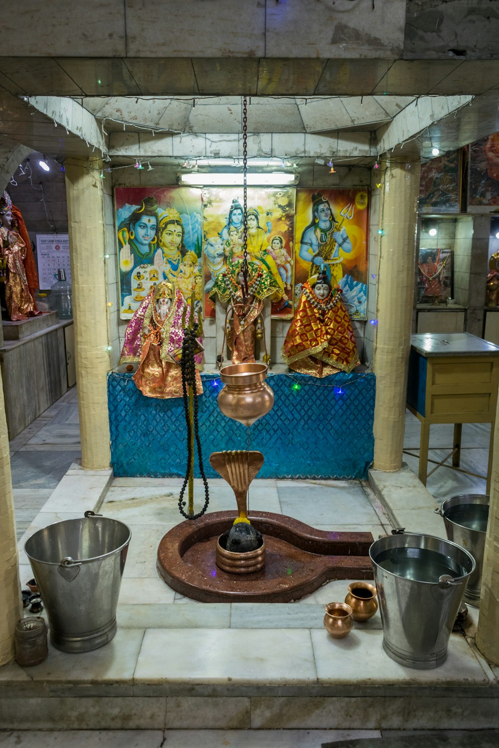 a shrine with a water fountain and metal buckets