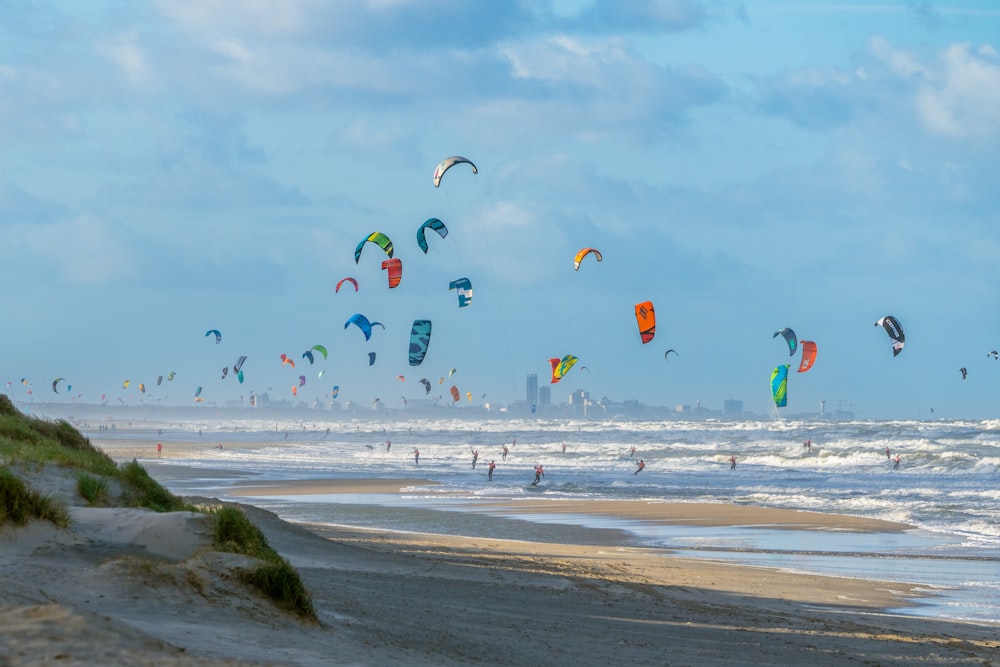 a group of people flying kites on top of a sandy beach