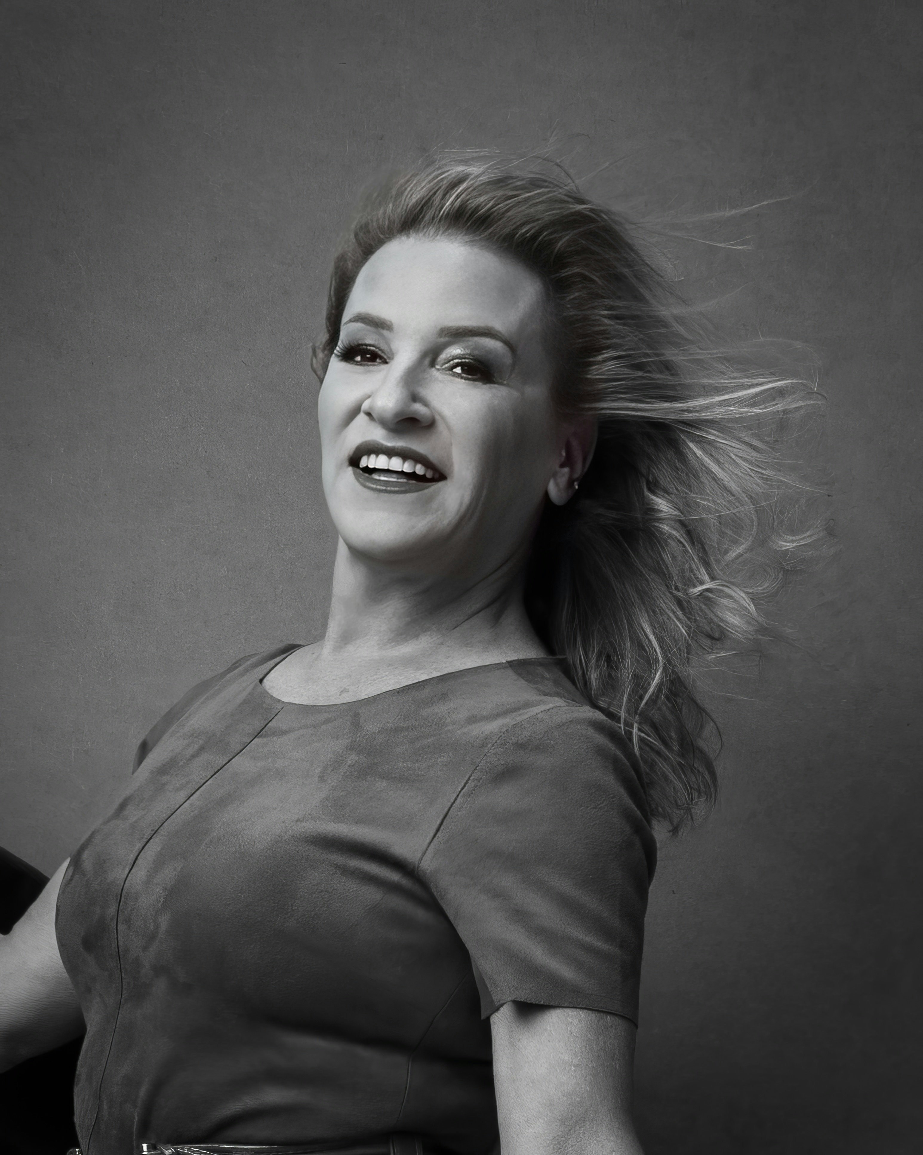 Portrait of a smiling woman in her 30s, casual clothing, natural light background