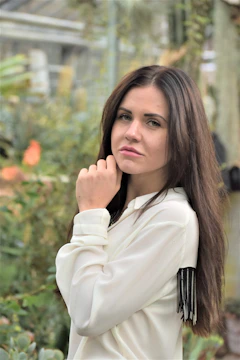 Woman wearing a fringed blouse outdoors in natural light.