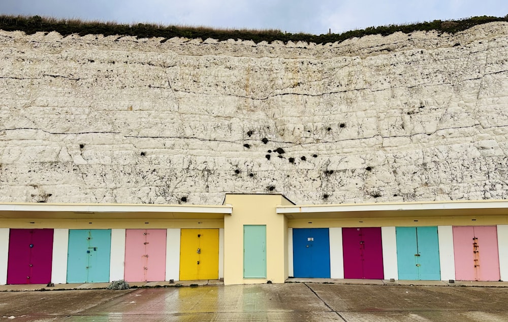 a row of colorful doors in front of a cliff