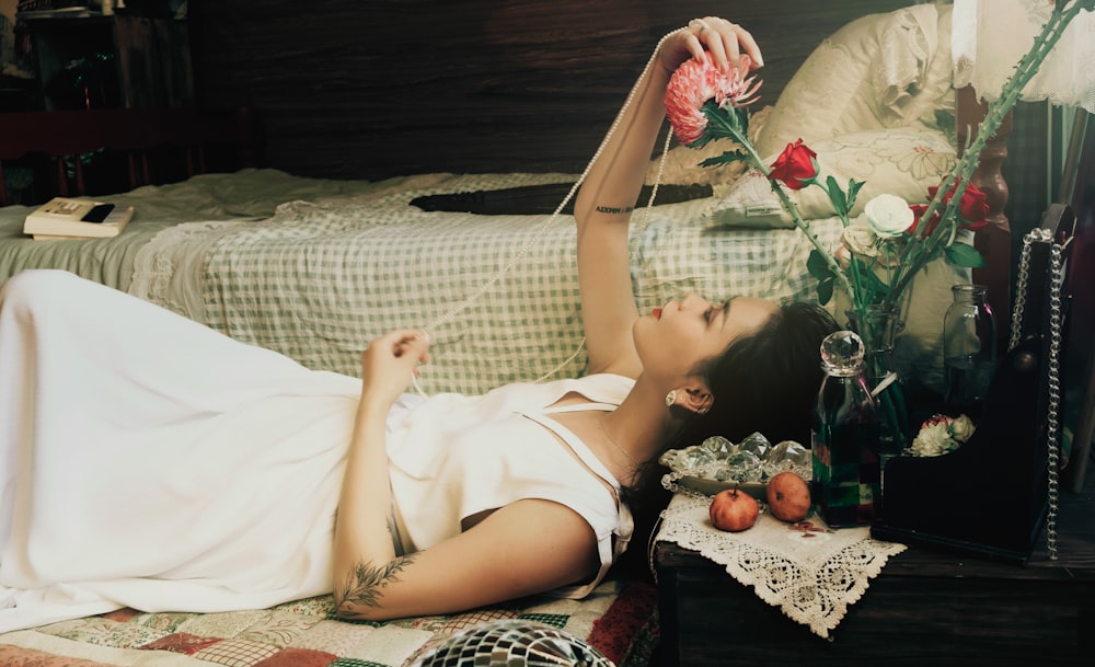 a woman laying on a bed with a flower in her hand