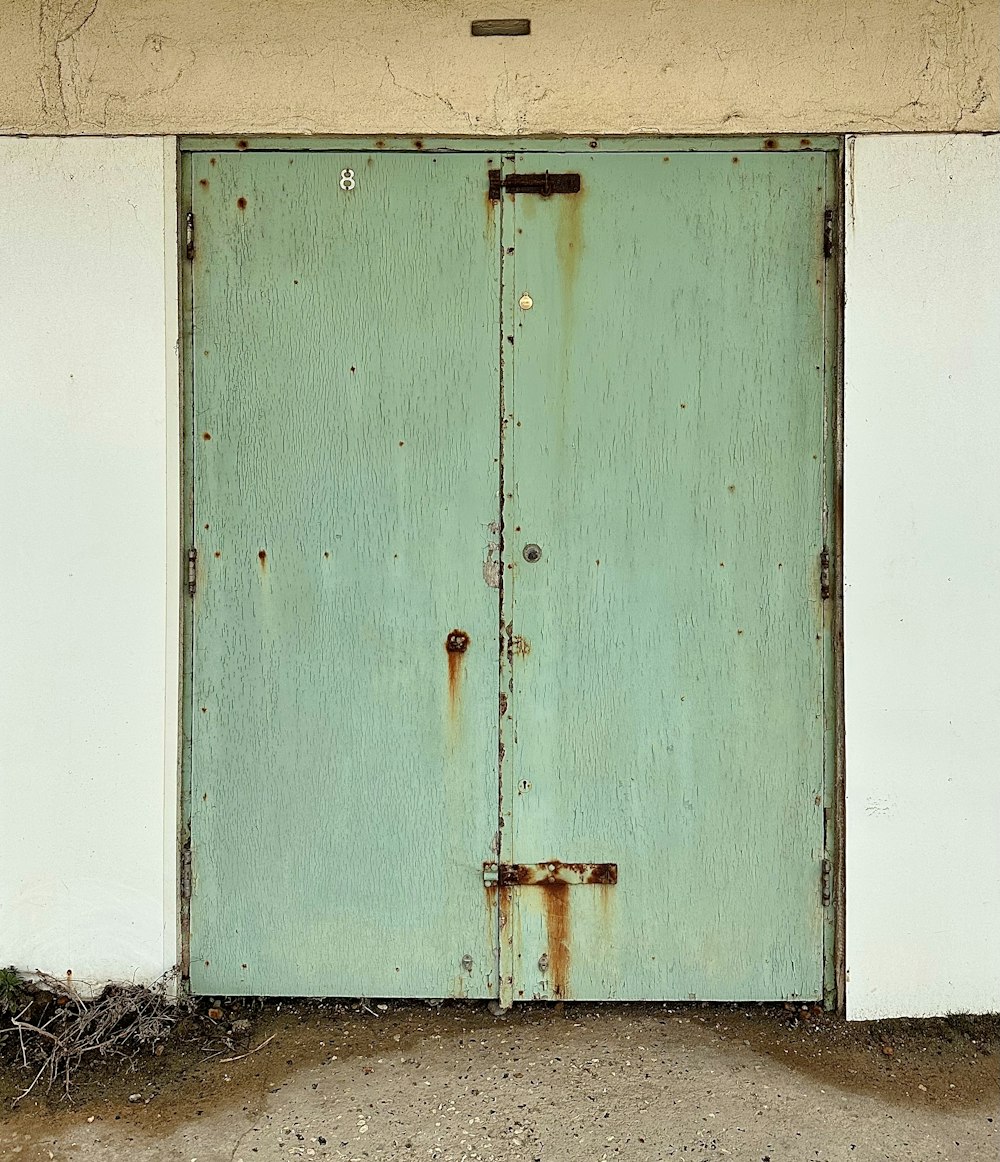 a green door with a rusted metal handle
