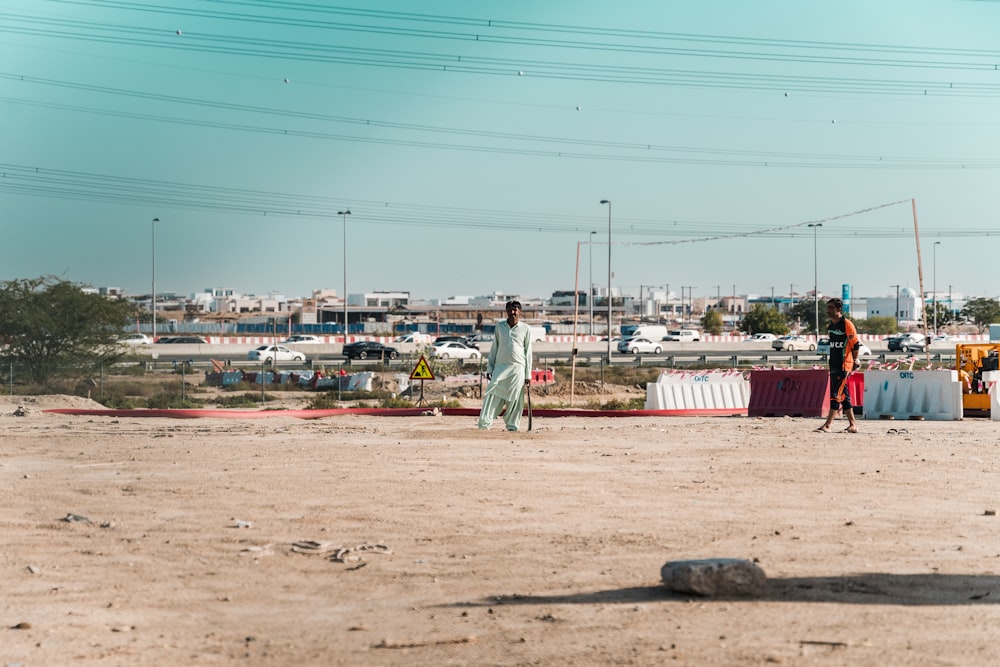 a couple of men standing on top of a dirt field