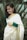 A woman gracefully draped in a cotton saree, smiling in a garden.