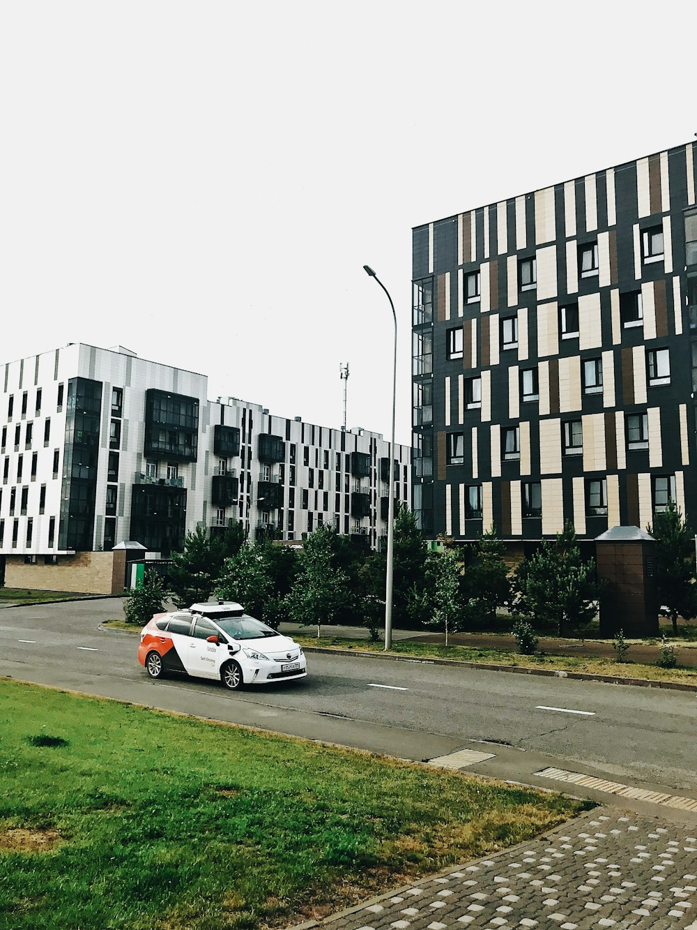 a white car driving down a street next to tall buildings