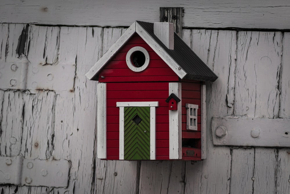 a red bird house with a green door