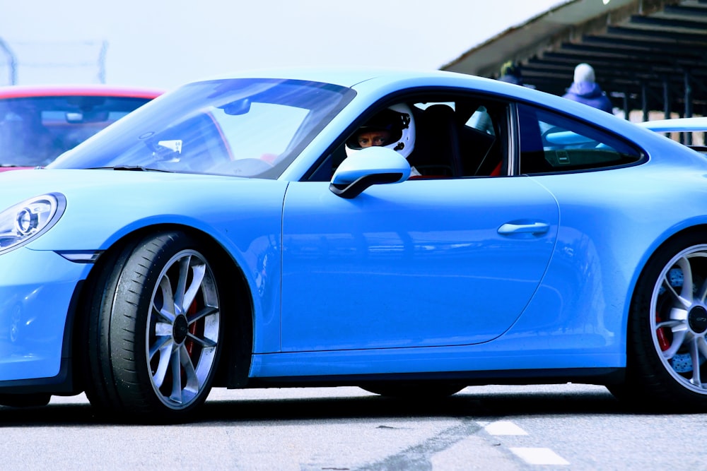 a blue sports car driving down a race track