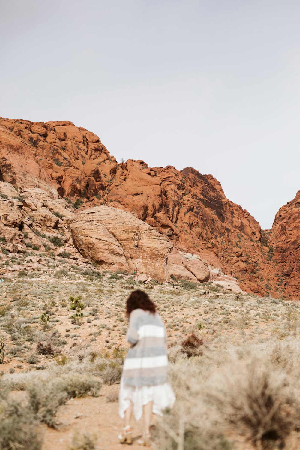 a woman in a white dress walking through the desert