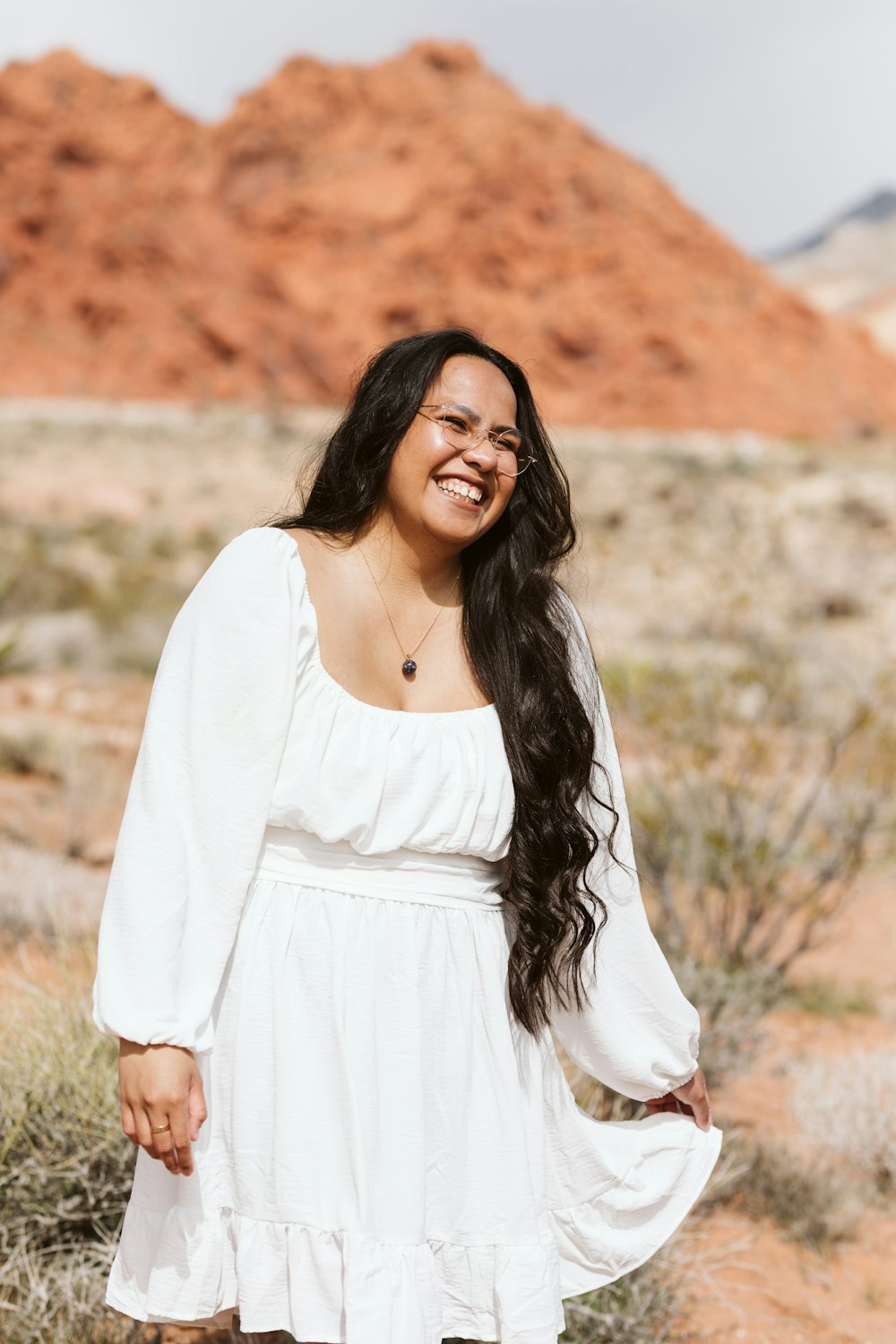 a woman in a white dress standing in the desert