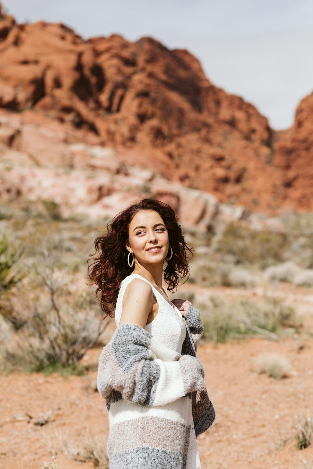 a woman standing in the desert with a mountain in the background