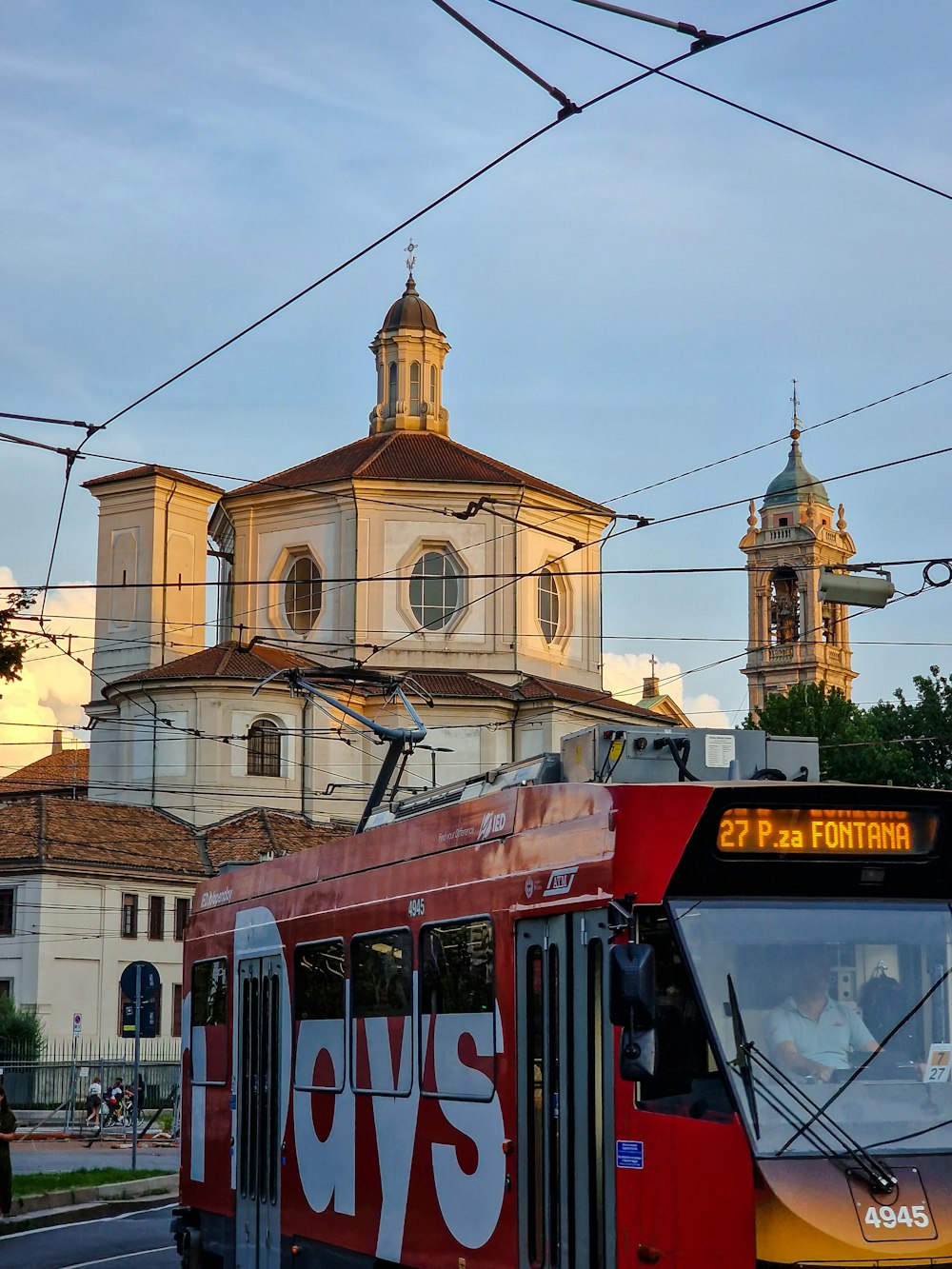 a red bus driving down a street next to a church