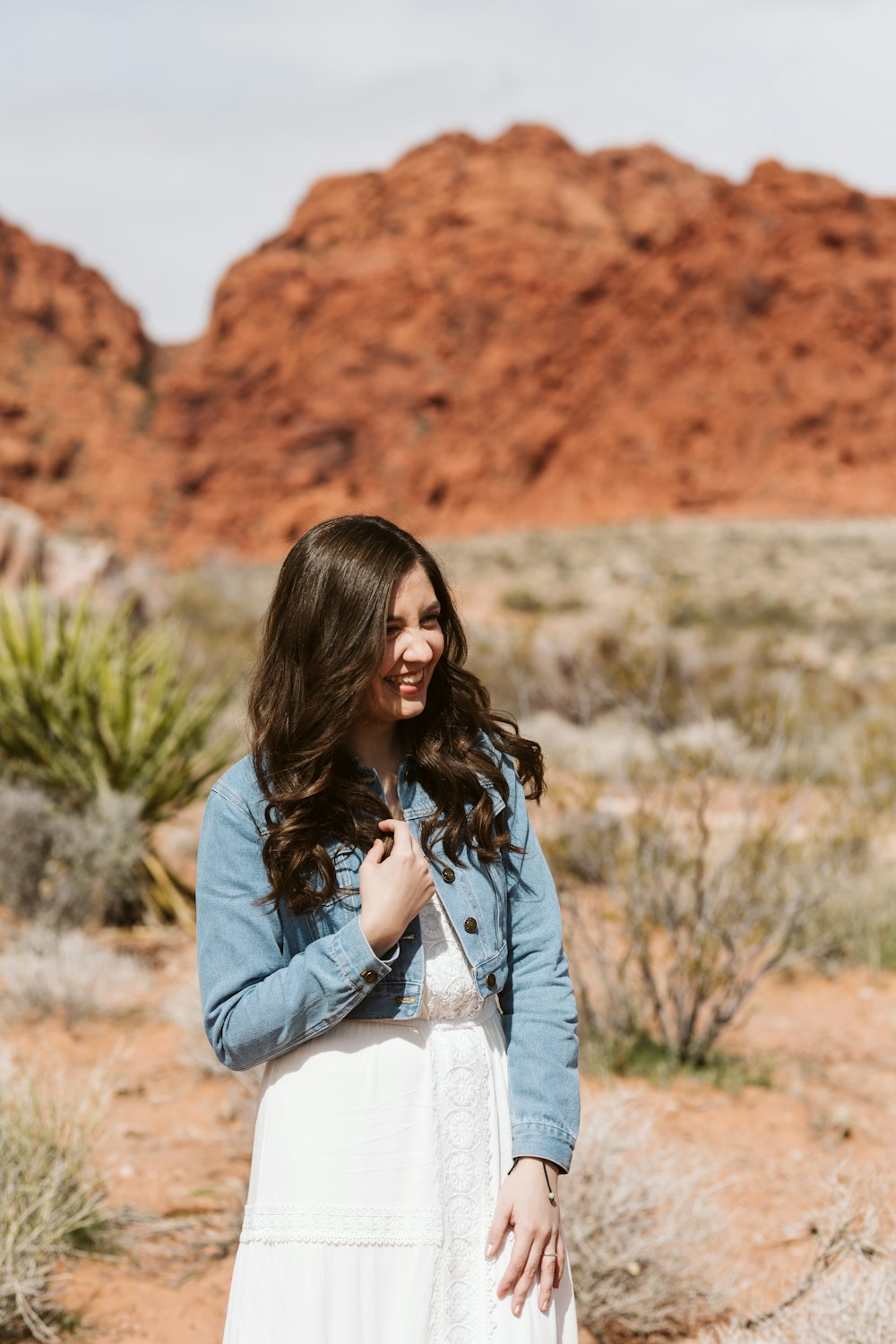 a woman in a white dress standing in the desert