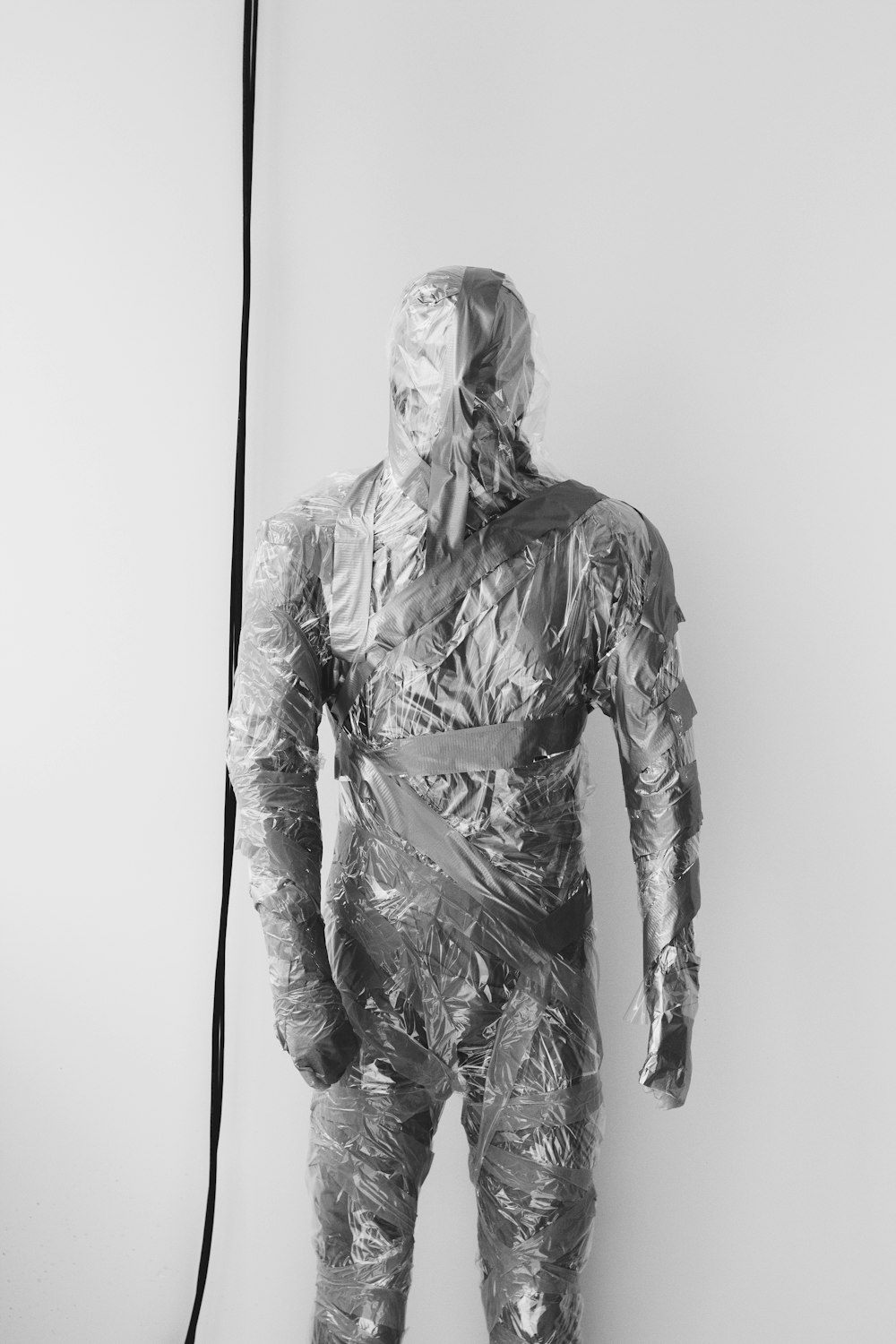 um homem em um terno de plástico em pé na frente de uma parede branca