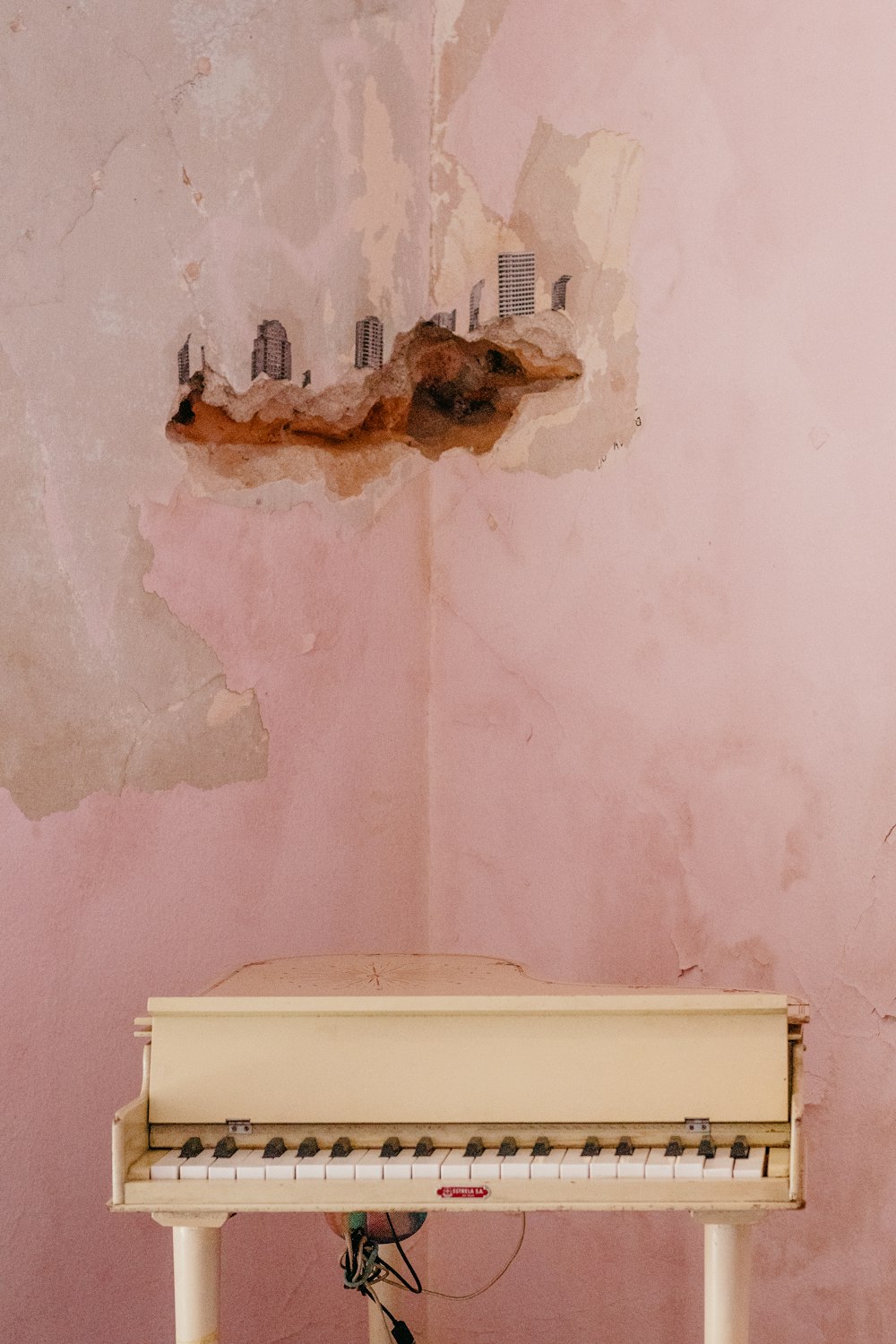 a white piano sitting in front of a pink wall
