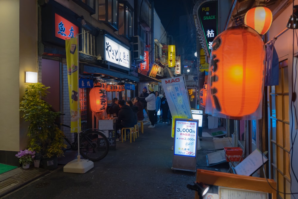 a narrow city street at night with people walking down it