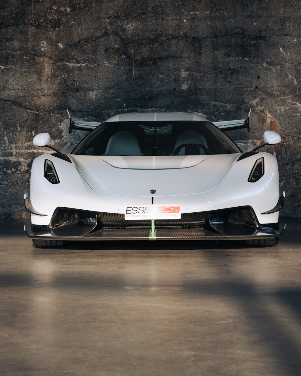 a white sports car parked in front of a stone wall