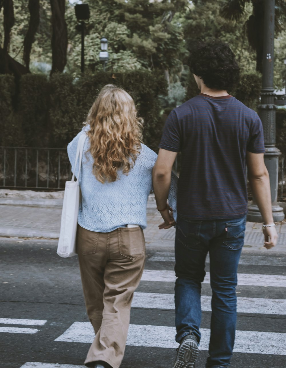 a man and a woman walking across a cross walk