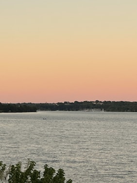 A serene view of Torch Lake at sunset with boats gently floating near the shore.