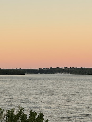 A peaceful lakeside view with a small boat floating near the shore at dawn.