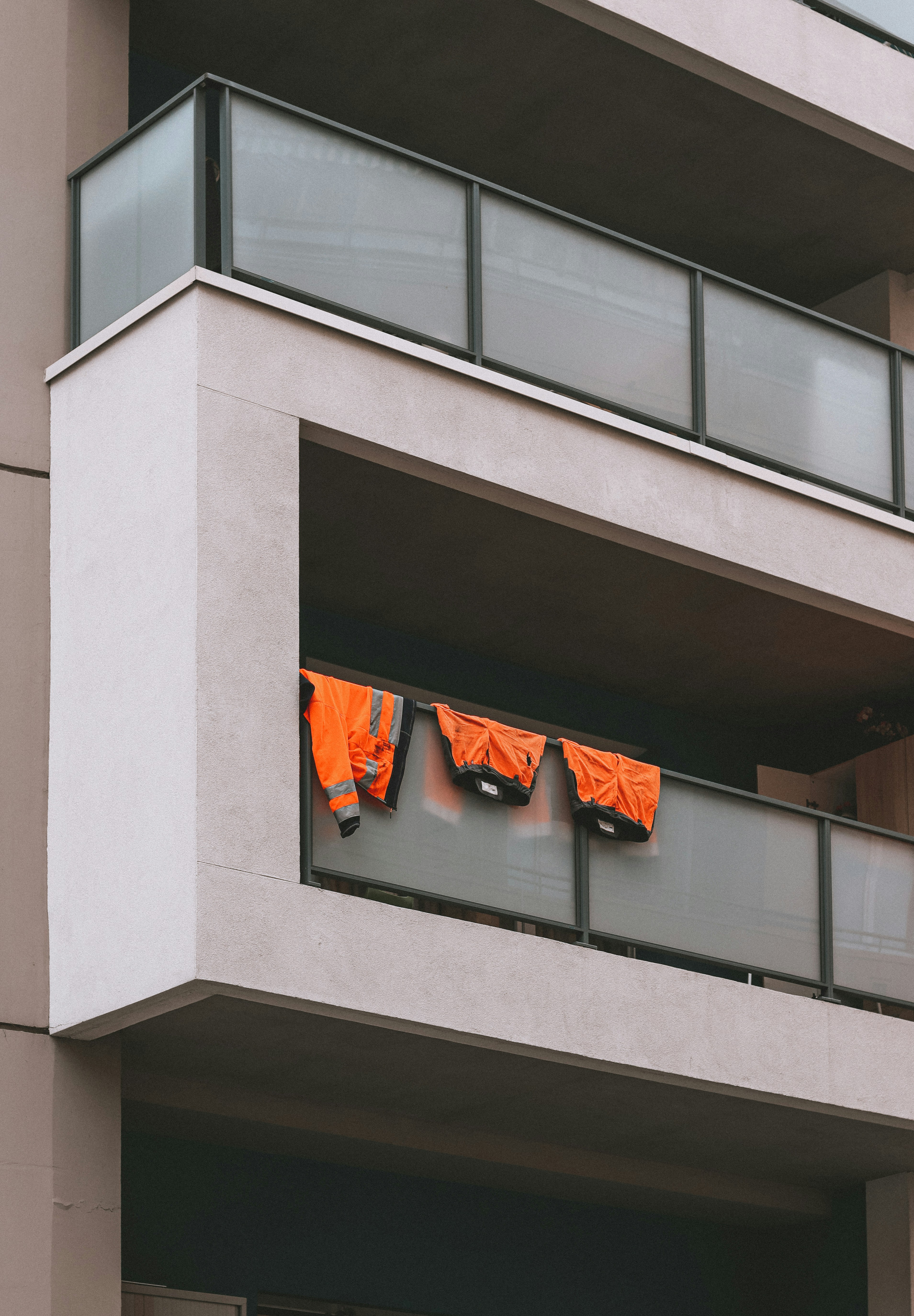 Orange high visibility safety vest hanging on bright warehouse rack, airy well-lit space
